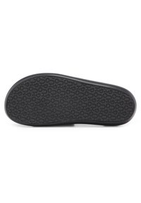 Czarna gumowa podeszwa buta z teksturowanym wzorem i powtarzającym się logo. Kształt jest smukły, odpowiedni do obuwia codziennego.