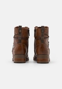 Bocanci din piele maro, de glezna, cu cusături decorative, fermoare în spate și accente contrastante de culoare maro închis. Partea superioară texturată și toc cu straturi.