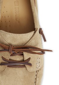 Beige Wildlederschuh mit braunen Lederbändern, glattem Innenfutter und dekorativen Nähten an den Seiten. Abgerundete Zehenform.