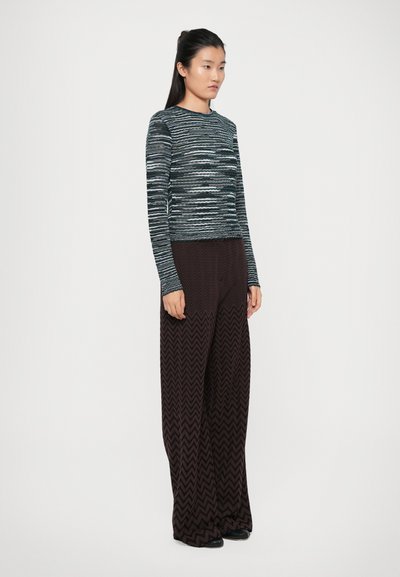 Top cu mânecă lungă în dungi, în nuanțe de navy și gri, asociat cu pantaloni cu picior larg, cu model în zigzag, în nuanță de maro. Textură netedă, siluetă ajustată.
