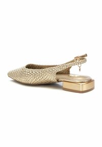 Zapato de slingback plano tejido en oro con punta afilada y tacón cuadrado. Presenta un acento metálico y una parte superior texturizada y transpirable.
