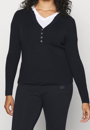 Marineblauer gerippter Pullover mit V-Ausschnitt und Knopfleiste mit fünf Knöpfen, kombiniert mit schwarzen Hosen. Glatte Textur und taillierte Passform.