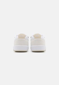 Hvite semskede og mesh sneakers med en beige hæl aksent, med et logo på baksiden. Rund form med en flat gummisåle.
