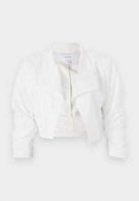 Krotká bílá bunda z hladké látky, s širokým límcem a řasenými rukávy, otevřená vpředu bez zapínání.