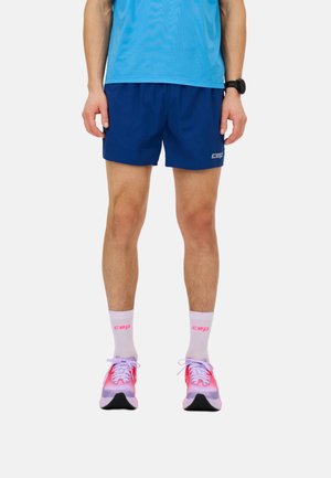 Male wearing blue athletic shorts, blue shirt, white socks with pink "cep" logo, pink and purple running shoes, and a black wristwatch.