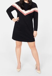 Vestido largo negro de manga larga con un patrón de bloques de color en forma de V en tonos blush y rosa claro. Tejido suave, escote redondo y corte relajado.