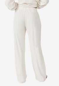 Brede loungebroek gemaakt van zachte, lichtcrème stof met een elastische tailleband en een gladde textuur. Casual en onversierd ontwerp.