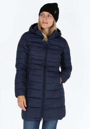 Navy padded coat with a zip front and hood, featuring horizontal quilted sections. Paired with a black beanie. Worn with blue jeans.