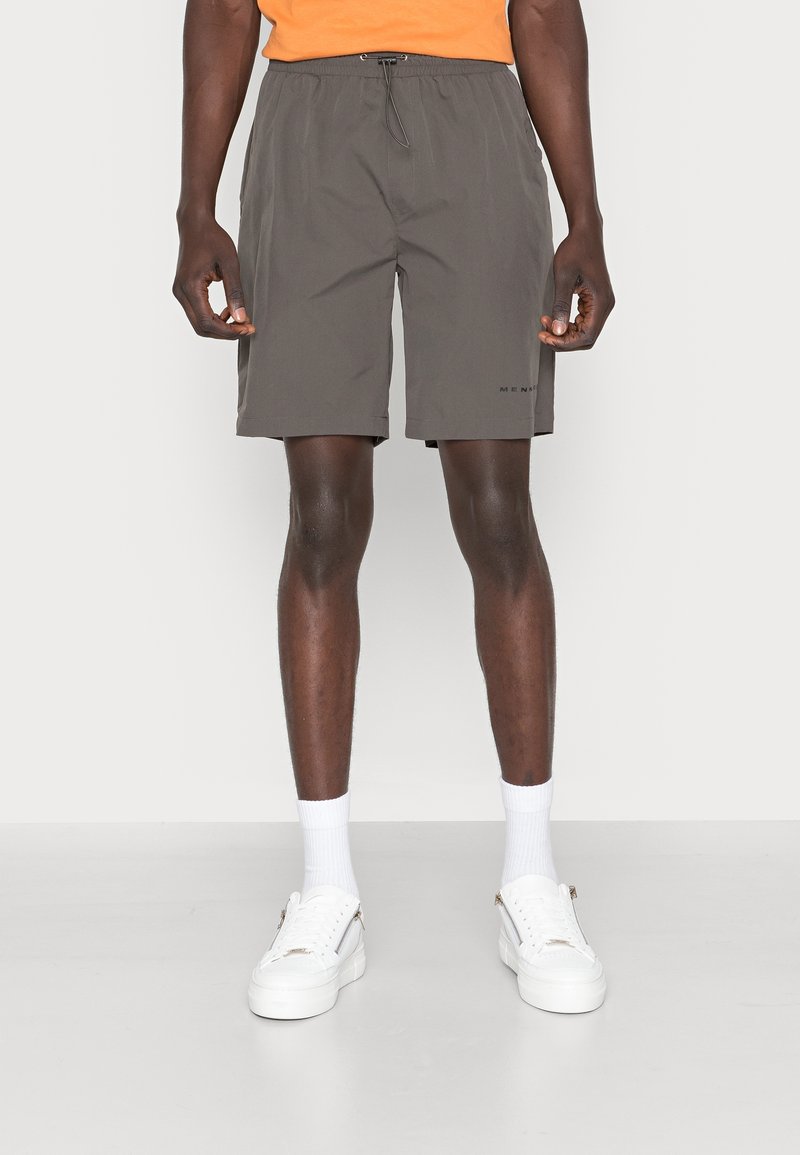 Shorts gris foncé pour hommes avec une taille élastique, un cordon de serrage, des poches latérales et des coutures plates. Portés avec des baskets blanches et des chaussettes.