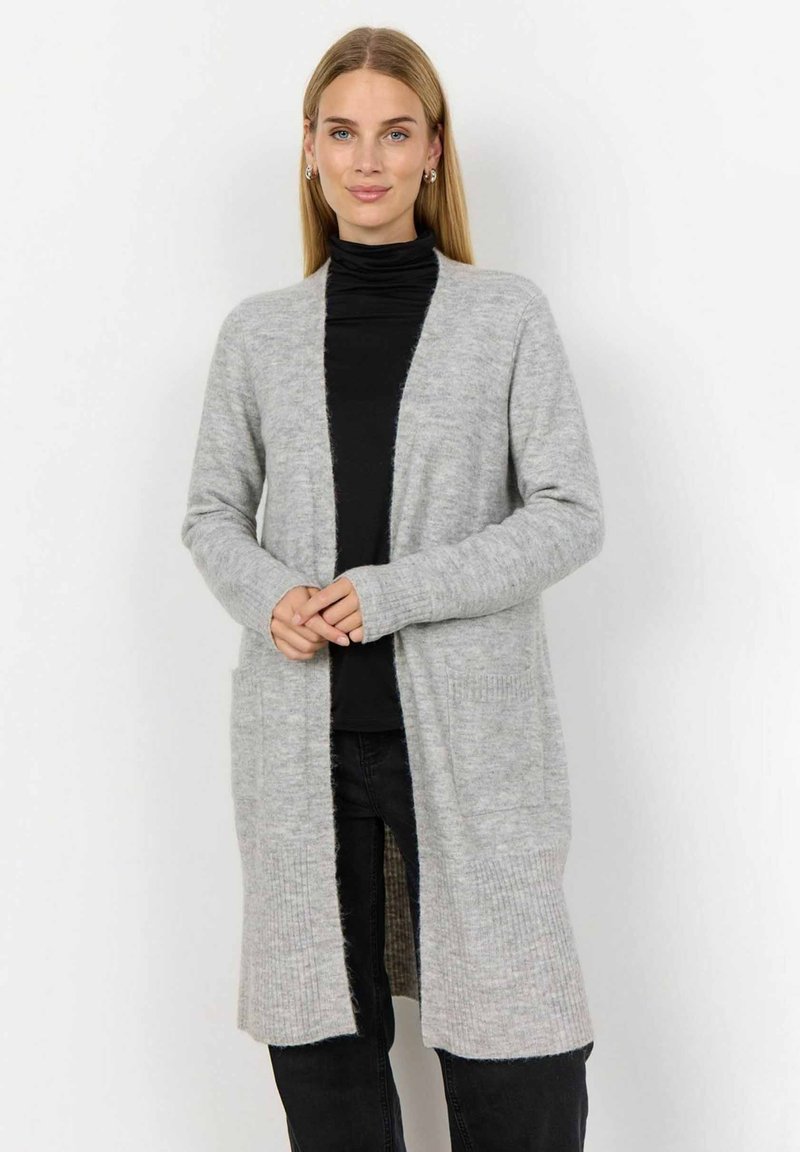 Grauer, langer Cardigan aus weichem Stoff, mit offenem Vorderteil, gerippten Bündchen und zwei vorderen Taschen. Getragen über einem schwarzen Rollkragenpullover.