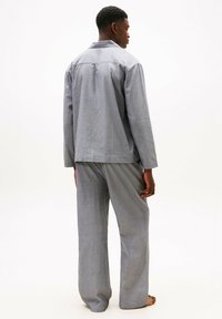 Grau gestreifter Pyjama-Set mit einem langärmligen Oberteil mit Kragen und passenden locker sitzenden Hosen. Weicher Stoff mit einer entspannten Silhouette.
