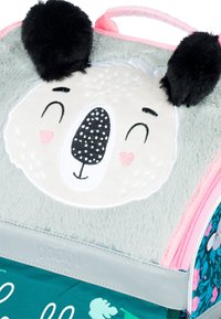 Weicher grauer Plüsch-Rucksack mit einem Koala-Gesicht, schwarzen Ohren, einem gemusterten türkisfarbenen Boden und rosa Reißverschluss-Akzenten. Markenname in den Gurt eingeprägt.