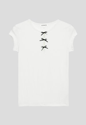 Weißes T-Shirt mit kurzen Ärmeln, das über einen runden Halsausschnitt verfügt und drei dekorative schwarze Schleifen entlang der vorderen Öffnung hat. Glatte Stoffstruktur.
