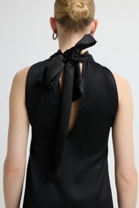 Czarny bezrękawnik z wysoką satynową kokardą z tyłu, głębokim rozcięciem typu keyhole i gładką fakturą. Prosty design i neutralny kolor.