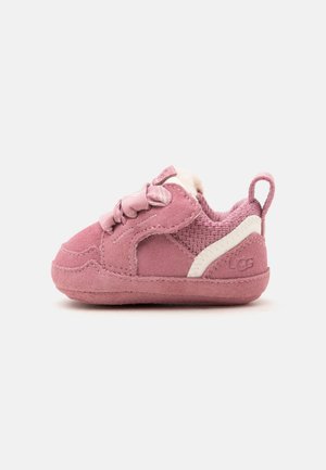 Zapatilla rosa para niño pequeño con suave ante, tela de punto, franja blanca de acento, cordones y tira para tirar sobre un fondo liso.
