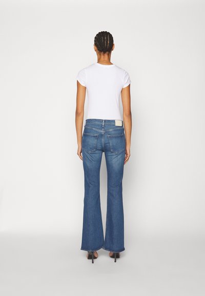 Jeans in denim svasati di colore blu medio con una leggera lavatura, dotati di un design a cinque tasche e un'etichetta cucita sulla vita posteriore.