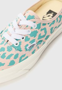 Vans sneakers with a pink fabric featuring a turquoise leopard print, white laces, and a cream rubber sole. Logo tag on the side.