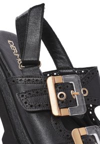 Sandal in pelle nera con dettagli perforati, fibbia in plastica trasparente e hardware in tonalità oro. Cinturino regolabile per una vestibilità sicura.