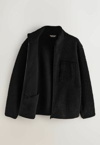 Černá zipová bunda vyrobená z texturované, huňaté látky s měkkým vnitřkem. Vybavena kordovým kapsou na levé straně.