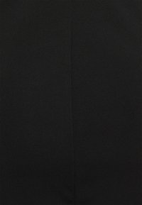 Närbild av svart tyg med en subtil vertikal söm ner i mitten, som visar en jämn, tätt vävd textur.