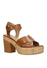 Sandali platform in pelle marrone con tacchi in sughero verticali, strappi incrociati e chiusura con fibbia per supportare la caviglia.