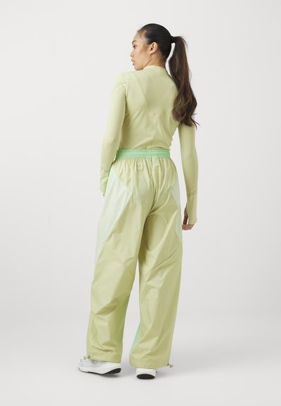 Ensemble de sport vert clair comprenant un haut ajusté avec des manches perforées et un pantalon large et décontracté avec des accents de poche contrastants.