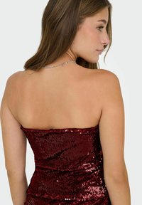 Bordeauxrode strapless top met pailletten en een aansluitend ontwerp, met een gestructureerd oppervlak en een gelaagde ruches-detail aan de zoom. Zilveren kettingaccent bij de hals.