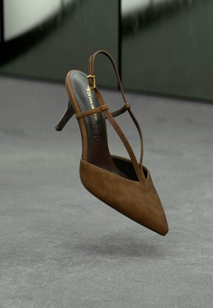 Bruine suède hoge hakken sandaal met een spitse neus, slanke enkelbandjes en een gouden gespaccent. Eenvoudig ontwerp, gestructureerd oppervlak.