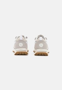 Lys grå sneakers med suede- og meshmateriale, et design med hvid stribe, struktureret gummisål og diskret branding på hælen og tungen.