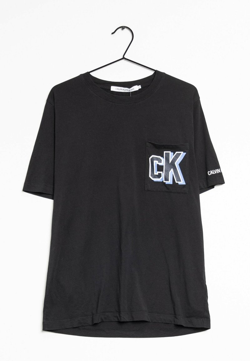 Camiseta negra de manga corta con un bolsillo en el pecho que presenta un logo "CK" en azul y blanco. La tela parece suave y tiene una textura similar al algodón.