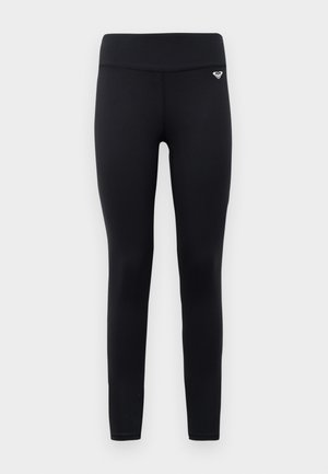 Black leggings made from stretchy, smooth material with a high waistband. Features a small logo detail near the waistband.