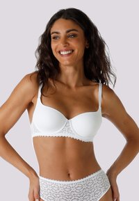 Reggiseno bianco con ferretto, dotato di coppa liscia e imbottita, e rifinito con pizzo nella parte inferiore. Spalline regolabili e un delicato dettaglio a contrasto.