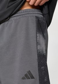 Γκρι αθλητικό παντελόνι με υφασμένη μαύρη πλαϊνή λωρίδα, ελαστική μέση και κεντημένο μαύρο λογότυπο. Μαλακό ύφασμα με λεία υφή.