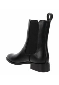Bota negra de cuero hasta el tobillo con panel lateral elástico, tirador en el talón y tacón bajo apilado.