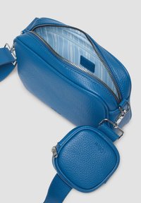 Blaues Leder-Crossbody-Bag mit strukturiertem Design, ausgestattet mit einem Reißverschluss und einem abnehmbaren runden Reißverschlussbeutel. Das Innere hat ein gestreiftes Futter.