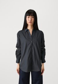 Dark gray shirt with a button-down front, long sleeves featuring lace accents, and a relaxed fit. Made of smooth fabric with a collar.