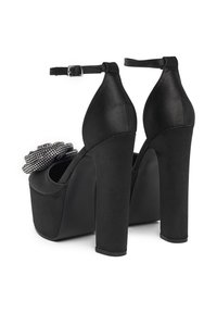 Černé platformové boty s saténovým povrchem, vysokým podpatkem, kotníkovým páskem a ozdobným květinovým detailem z korálků na přední straně.