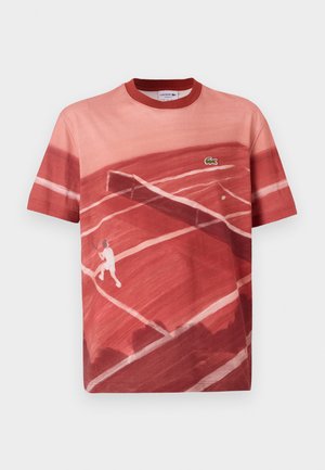 Punane puuvillane T-särk, millel on tennisisti graafika, segatud punaste toonidega ja ümmargune kaelus. Lacoste logo aksent rinnal.