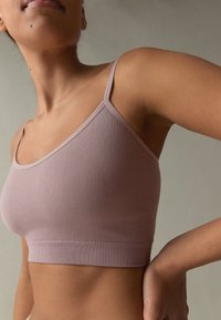 Bralette lilla chiaro a coste con spalline sottili e silhouette aderente, caratterizzata da una texture morbida e una fascia elastica sul fondo.