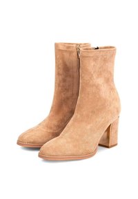 Un par de botas de ante beige hasta el tobillo con tacones de bloque y cremalleras laterales, que cuentan con un diseño de punta afilada y detalles de costura.