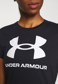 Juodas medvilnės marškinėliai su dideliu baltu "Under Armour" logotipu ant krūtinės. Trumpi rankovės, apvalus kaklas ir laisvas fasonas.