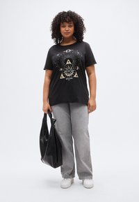 Černé bavlněné tričko se zlatým nebeským motivem, kulatý výstřih, krátké rukávy. Šedé džíny se širokými nohavicemi a černá texturovaná kabelka na rameno.