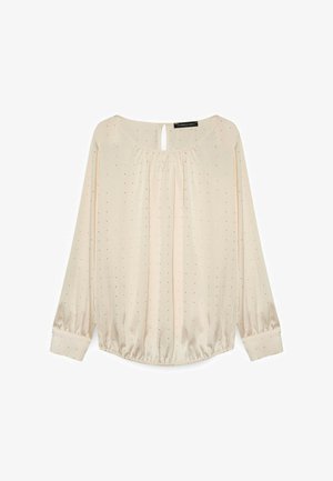 Lys beige langærmet bluse med en samlet halsudskæring, nøglehul detalje, elastriske manchetter og små sorte polka dots hele vejen igennem.