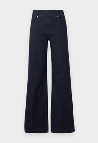 Σκούρο μπλε τζιν ψηλόμεσο με φαρδιά ποδιά, ραφές μπροστά και θηλιές για ζώνη σε απλό ανοιχτό φόντο.