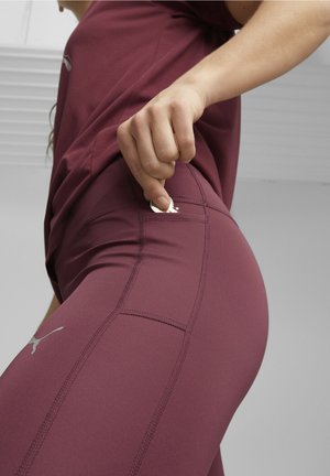 Leggings de sport bordeaux au design épuré, avec des détails de couture et une poche latérale, associés à un haut assorti.