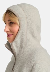Veste à capuche en polaire grise claire avec une finition texturée, dotée d'une fermeture éclair et d'une bordure beige contrastante le long des bords.
