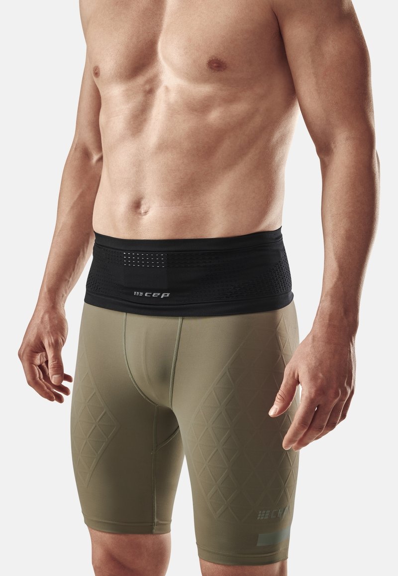 Olivegrüne Kompressionsshorts mit Rautenmuster, ausgestattet mit einem schwarzen, elastischen Bund mit Mesh-Details und einem Logo.