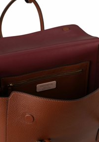 Bruine leren handtas met een gestructureerd oppervlak, een bordeauxrode binnenkant en een ritsspaanzak. Het ontwerp heeft stevige handvatten en een knoopsluiting.