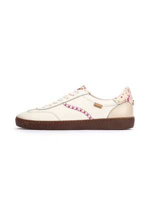 Zapatilla deportiva de color crema con suela de goma marrón, que presenta costuras rojas decorativas y un acento trasero con patrón.