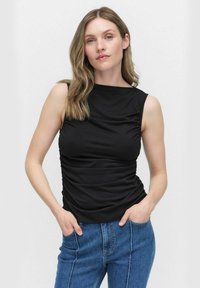 Svart utan ärmar topp med rynkade sidodetaljer, rund halsringning och mjukt tyg, i kombination med högmidjade blå jeans.